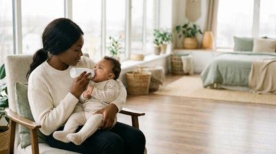 A mother giving her baby an unhurried bottle feed in a low armchair, the two of them looking at each other