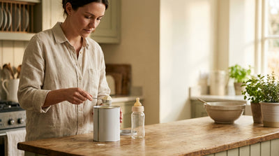 A mother levelling a scoop of formula powder over an open tin, a clean bottle ready beside it