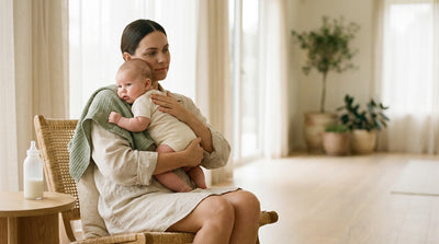 A mother holding her baby upright against her shoulder after a feed, a muslin cloth over her shoulder