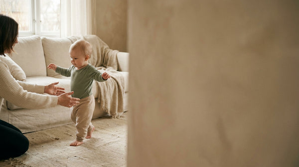 11 month old baby cruising along the sofa toward a parent's outstretched hands