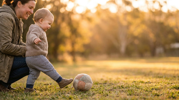 19 month old toddler running toward a ball in a field at sunset