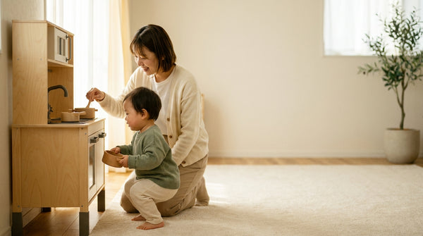 20 month old toddler playing at a toy kitchen while a parent kneels beside