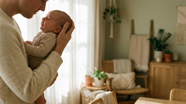 Father holding his 7 week old baby upright against his chest at home
