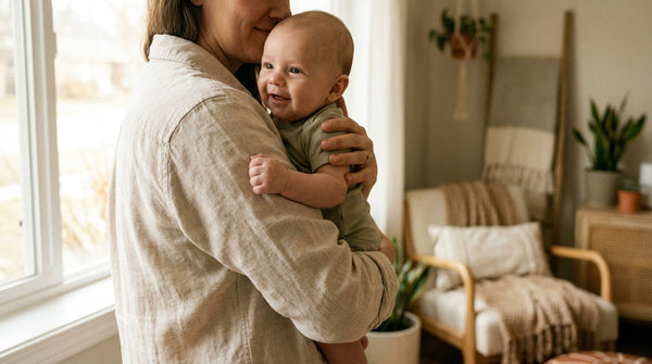 Mother holding her smiling 12 week old baby against her shoulder
