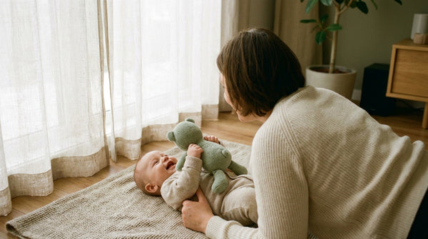Parent leaning over their 15 week old baby playing with a plush toy on the floor