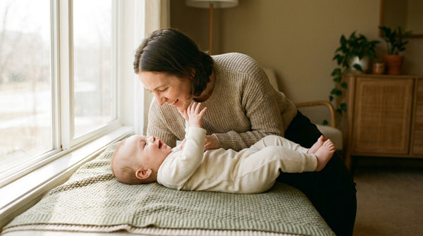 Mother lying beside her 16 week old baby on a play mat by a window