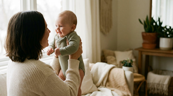 Mother lifting her smiling 23 week old baby into the air